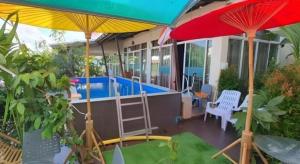 un patio avec deux parasols et une piscine dans l'établissement Green Home Resort, à Surat Thani