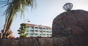 ein Hotel mit einer Palme vor einer Steinmauer in der Unterkunft Jeju Sunbeach Hotel & Resort in Jeju-do