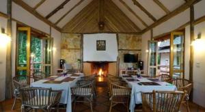 ein Esszimmer mit weißen Tischen und Stühlen und einem Kamin in der Unterkunft Chiangkham Luang Resort in Ban Huai Sai