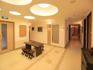 a room with a table and benches and a hallway at Dalian Household Theme Hotel Huanghe Road Branch in Dalian