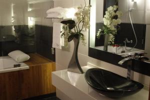 a bathroom with a black sink and a vase with flowers at Luxor Hotel in Jounieh