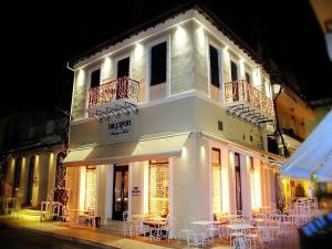 a white building with tables and chairs in front of it at Spon Boutique Hotel in Nafpaktos