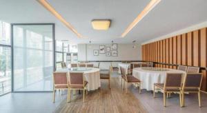 une salle à manger avec deux tables et chaises et des fenêtres dans l'établissement Zhaoqing Shanshui Fashion Hotel Duanzhou Road Branch, à Zhaoqing