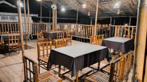 ein Esszimmer mit Tischen und Stühlen sowie einem schwarzen Tischtuch in der Unterkunft Barhoitoka Homestay in Kāziranga