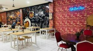 um restaurante com mesas e cadeiras e uma parede de tijolos em Hotel Huswah Airport em Jacarta