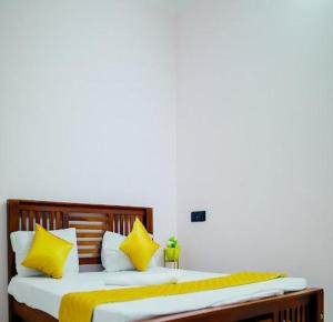 um quarto com uma cama com almofadas amarelas e brancas em The Sunshine Villa em Pondicherry