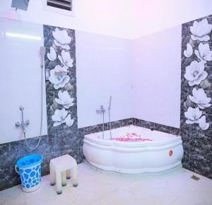 um banheiro com banheira em um quarto com flores na parede em The Sunshine Villa em Pondicherry mais 12 fotografias