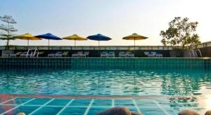 une piscine avec chaises et parasols dans l'établissement Rashmi's Plaza Hotel Vientiane, à Ban Souanmon