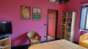 a bedroom with a pink wall with a bed and a tv at Oasi di Frattamaggiore in Frattamaggiore