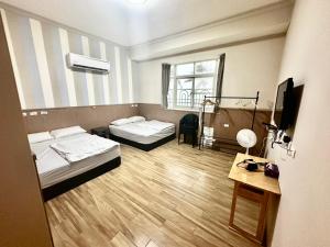Zimmer mit 2 Betten, einem Tisch und einem TV in der Unterkunft 小琉球旭日之外海景包棟 in Xiaoliuqiu + 2 Fotos