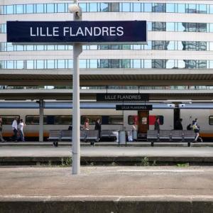 a sign at a train station with people waiting for a train at Appartement typique Gare Lille Flandre centre ville in Lille