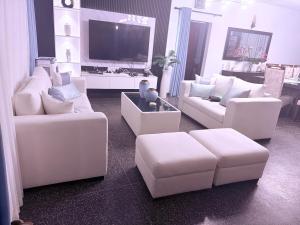 sala de estar con sofás blancos y TV de pantalla plana en Bernies Blue Heaven, en Colombo