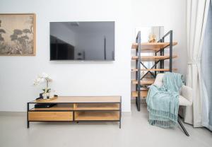 ein Wohnzimmer mit einem TV, einem Tisch und einem Stuhl in der Unterkunft Cosy Studio Apartment in Blue Bay Walk in Schardscha