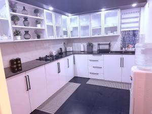 een witte keuken met witte kasten en een zwarte vloer bij Bernies Blue Heaven in Colombo