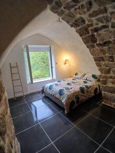 a bedroom with a bed in a stone wall at Gîte au cœur des Gorges du Tarn in Saint-Rome-de-Dolan