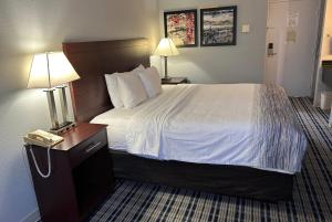 a hotel room with a bed with a phone next to it at AmericInn by Wyndham Mosinee Central Wisconsin Airport in Mosinee