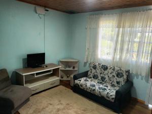 a living room with a couch and a tv and a chair at Casa Villagio - CONDOMÍNIO in Gramado