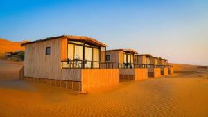 a row of small buildings in the desert at SAMA Al Areesh Desert Camp in Al Qābil