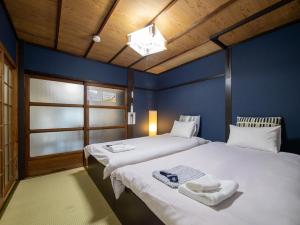 two beds in a room with blue walls at kyomachiya-京町家Oneworld十条-Jujo in Kyoto