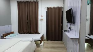 ein Hotelzimmer mit zwei Betten und einem Fernseher in der Unterkunft Barhoitoka Homestay in Kāziranga