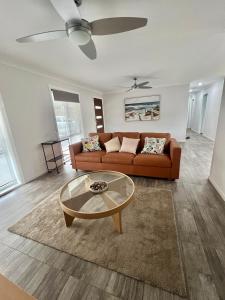 a living room with a couch and a glass table at The Burra Spa, Games & Beach House in Culburra Beach