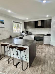 a kitchen with a counter and stools in it at The Burra Spa, Games & Beach House in Culburra Beach