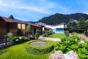 a garden with flowers and plants in front of a building at Foxoso Misty Oaks - Hotel & Resort in Bhowāli