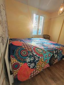 Un dormitorio con una cama con una colcha colorida. en Le grand gîte du Causse, en Cuq-Toulza