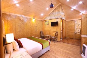 a bedroom with a bed in a room with wooden walls at Foxoso Misty Oaks - Hotel & Resort in Bhowāli
