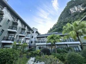 a building with palm trees in front of a mountain at Yangshuo Greenlotus Hotel in Yangshuo