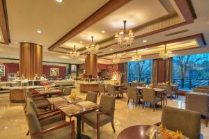 a restaurant with tables and chairs in a room at New Century Manju Hotel Shanghai New International Expo Center in Shanghai