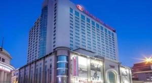 un grand bâtiment avec une enseigne au sommet dans l'établissement Ramada Plaza Shenyang Citycenter, à Shenyang