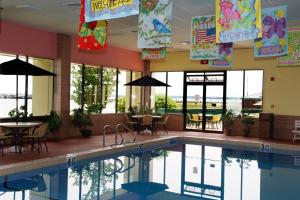 a swimming pool with tables and chairs in a building at Tawas Bay Beach Resort & Conference Center in East Tawas