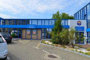 un bâtiment bleu avec des voitures garées dans un parking dans l'établissement Motel Carmen, à Baia Mare