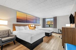 a hotel room with a bed and a chair and a tv at Days Inn by Wyndham Liberty Monticello in Ferndale +34 photos