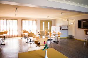 an empty room with chairs and tables and a refrigerator at Cherry Blossom Motor Inn in Young