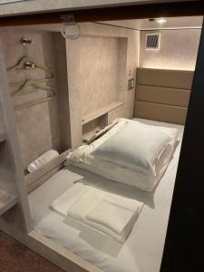 Cette petite chambre comprend un lit avec des draps blancs. dans l'établissement Book Tea Bed SHIBUYA, à Tokyo 7 autres photos