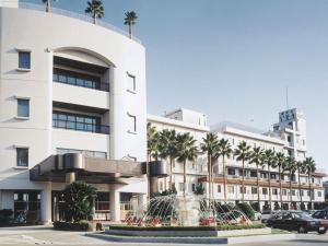 a white building with palm trees in front of it at Hotel Ito in Nishi-sakamoto