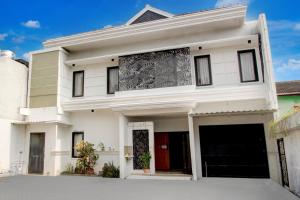 ein weißes Haus mit schwarzen Fenstern in der Unterkunft Hotel O Rumah Daun Guesthouse Jogja in Demangan