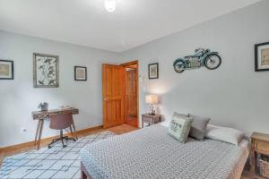 Un dormitorio con una cama y un escritorio con una motocicleta en la pared. en Mountain Retreat with River Views Near Sunday River and Year-Round Adventure, en South Rumford