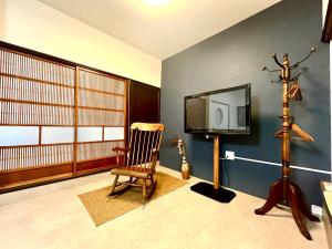 a living room with a tv and a rocking chair at CatNook 猫ちぐら in Matsumoto
