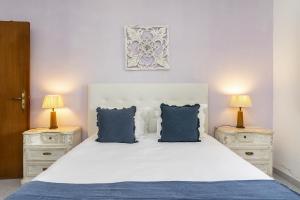 een slaapkamer met een wit bed met blauwe kussens bij Villa Oasis - Pool & Garden in Santa Marta +29 foto's