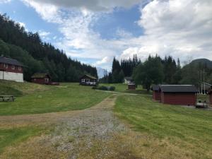 a dirt road in a field with houses and trees at Døskelandslia Camping in Sygna