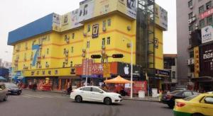 une voiture blanche garée devant un bâtiment jaune dans l'établissement 7 Days Inn Dongguan Changping Railway Station, à Dongguan