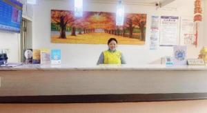 a woman standing behind a counter in a store at 7 Days Inn Guiyang Qianlingshan Park Beijing Road Metro Station in Guiyang