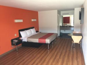 um quarto de hotel com uma cama com paredes cor de laranja em Motel 6-San Antonio, TX - South WW White Rd em San Antonio