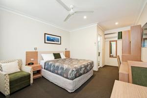 a bedroom with a bed and a chair and a table at Colonial Terrace Motor Inn in Raymond Terrace