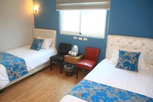 a small room with two beds and a chair at 500Km Home in Hualien City