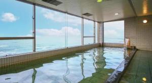 an indoor swimming pool with a view of the ocean at Hotel AreaOne Banjinmisaki in Kashiwazaki