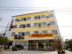 a yellow building with a car parked in front of it at Shell Nanjing City Qixia District Baguazhou Hotel in Nanjing